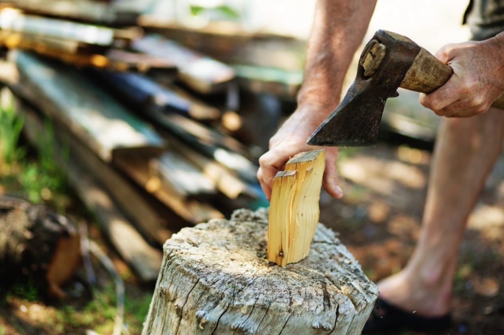 Carefully chopping firewood kindling with hatchet